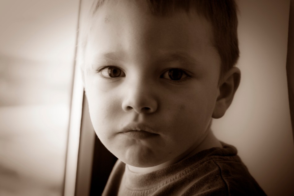 A child looks directly at a camera making a serious face in sepia tone