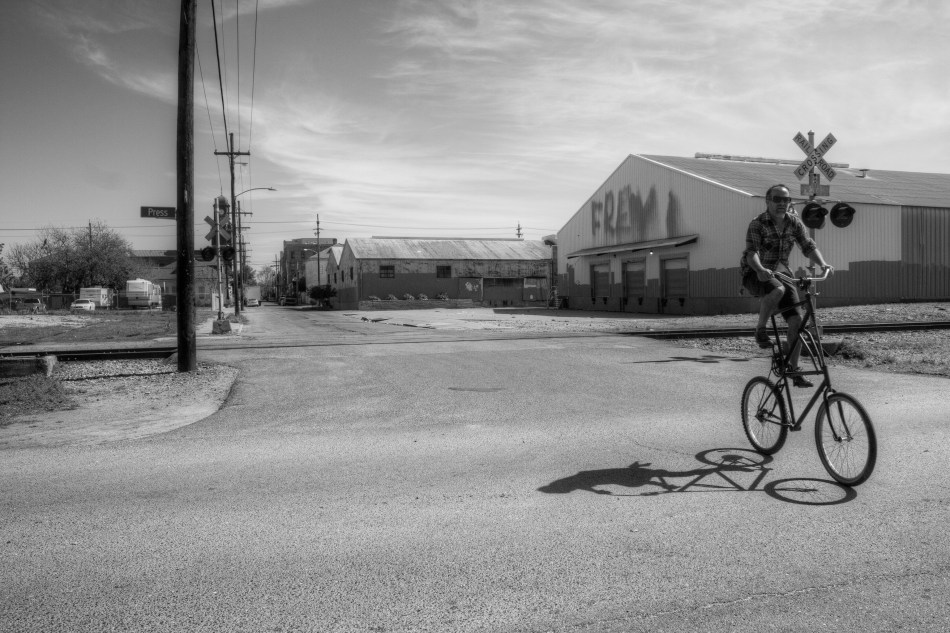 A man riding a tall bike through the Bywater Neighborhood of New Orleans