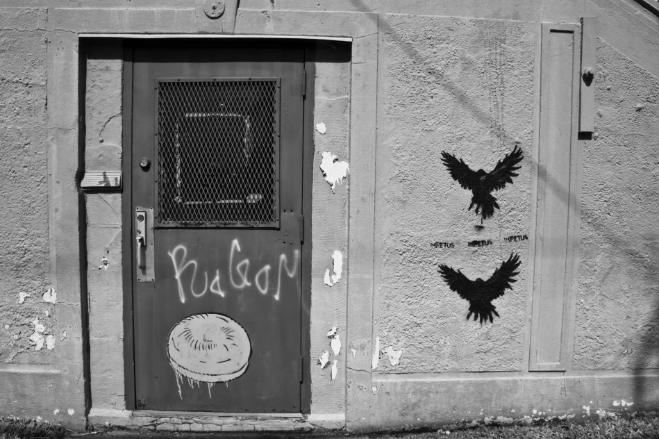 A black and white image of a metal door with graffitti in the 7th Ward of New Orleans, Louisiana