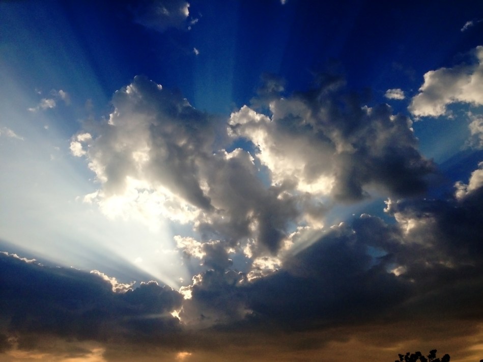 Beams of sunlight shining through clouds in a blue sky